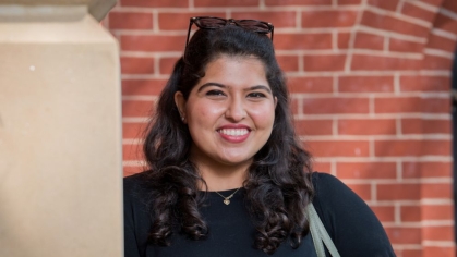 Student smiling in front of a building on Rutgers campus