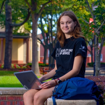 Student on their laptop on a summer campus day