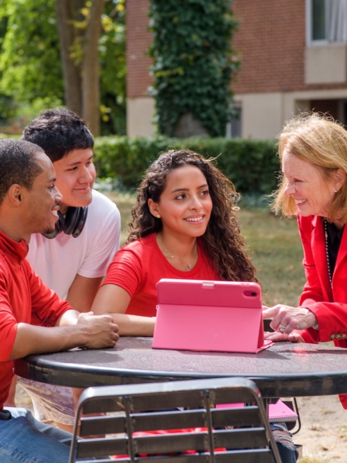 A professor teaching three students outside