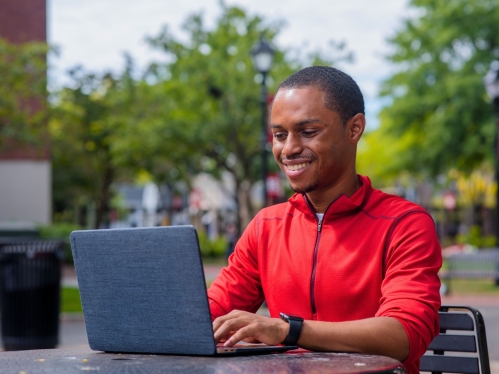 Student sitting at a table outside using their laptop