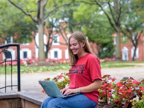 Student sitting outside on their laptop during summer