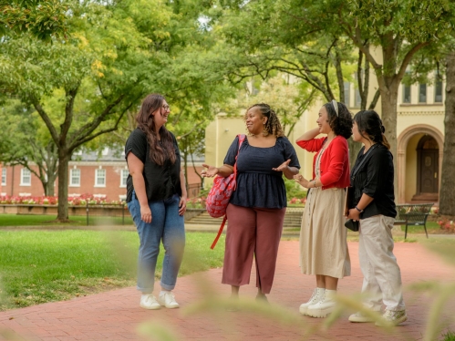 Three students and an instructor gathered talking on the Rutgers campus
