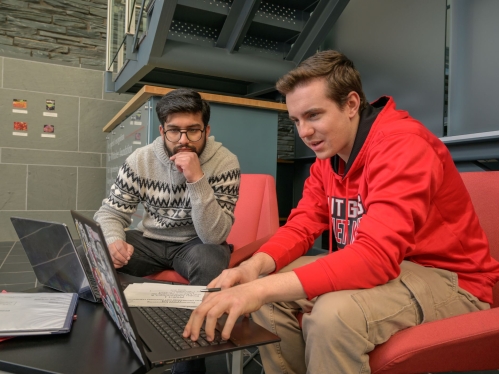 Students sitting inside working on their laptops